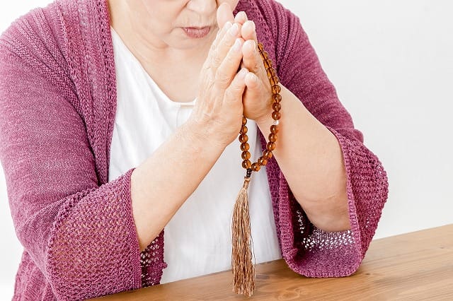 数珠を持って祈る女性